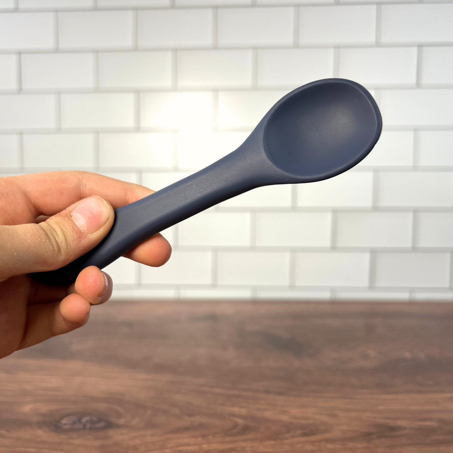 Hand holding blue spoon.