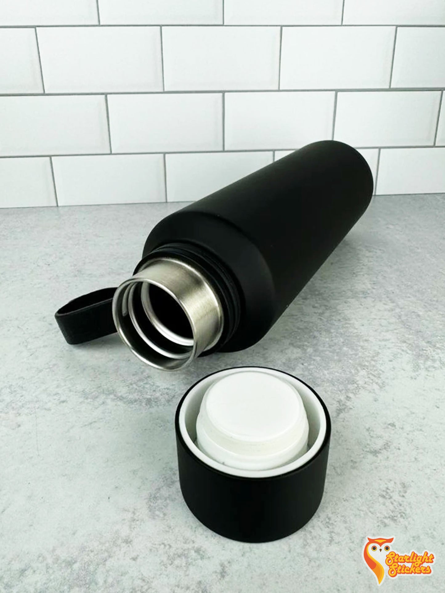 Black tumbler laying table with its lid off.