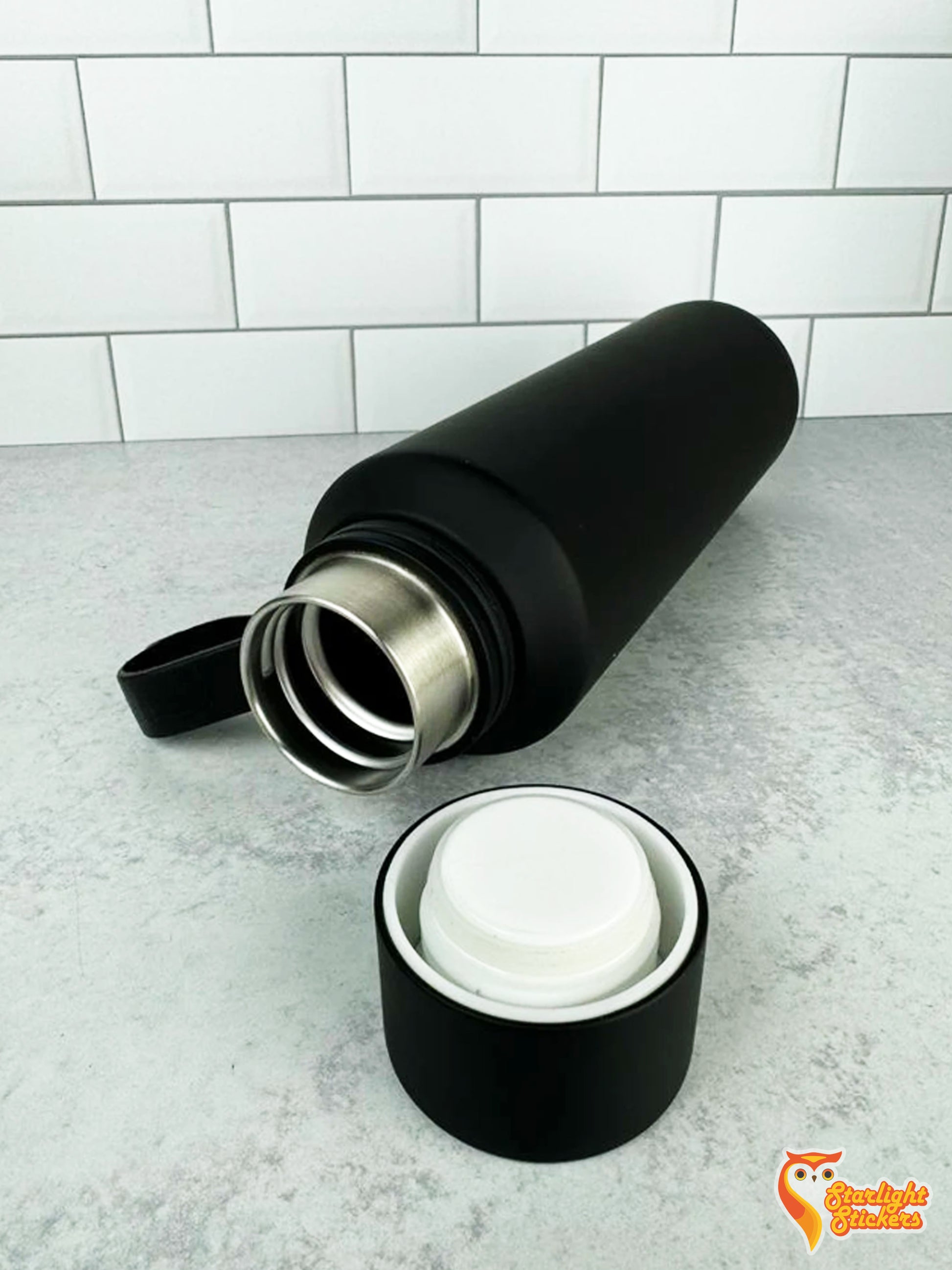 Black tumbler laying table with its lid off.