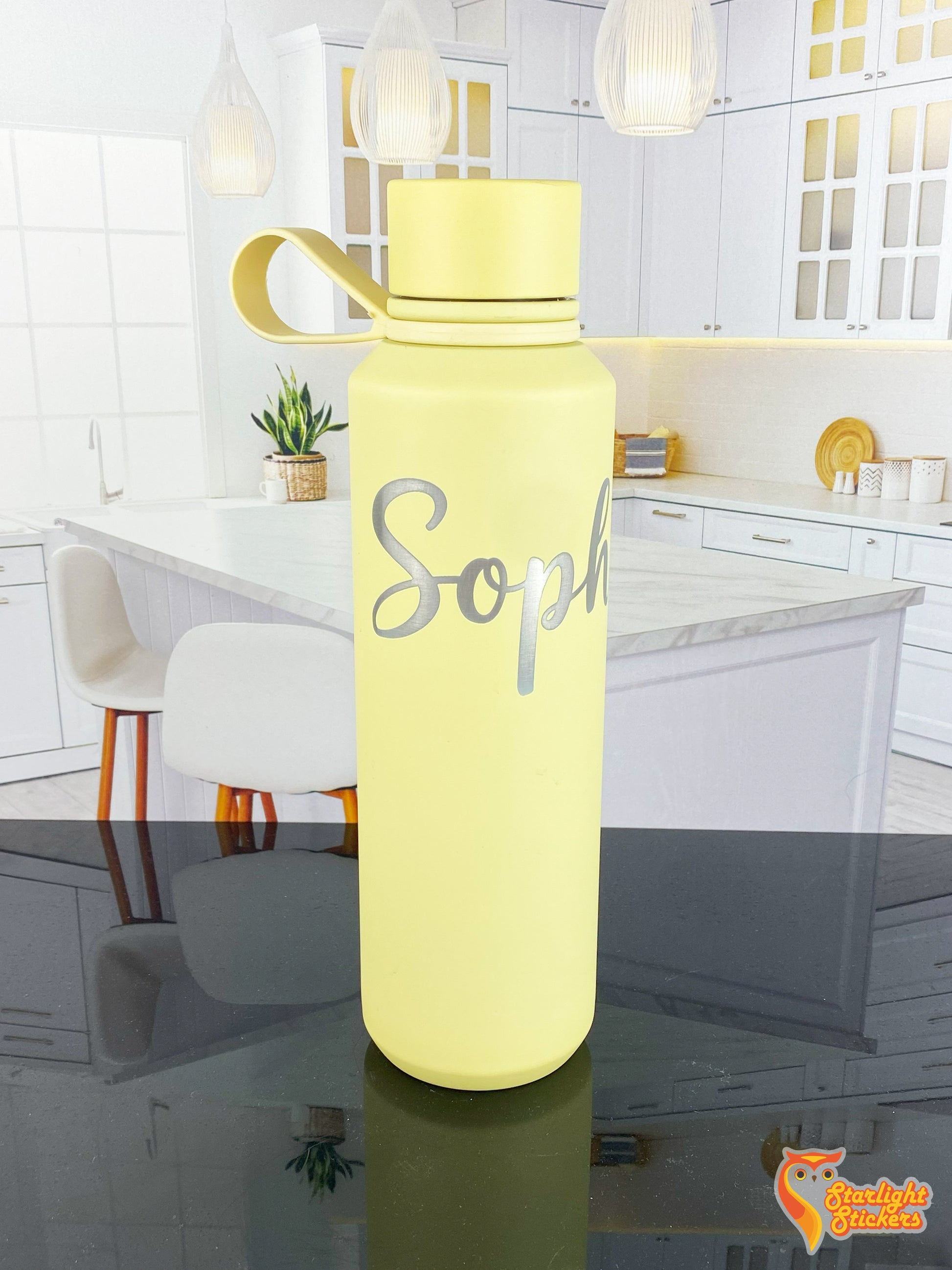 Yellow engraved tumbler on a black reflective table.