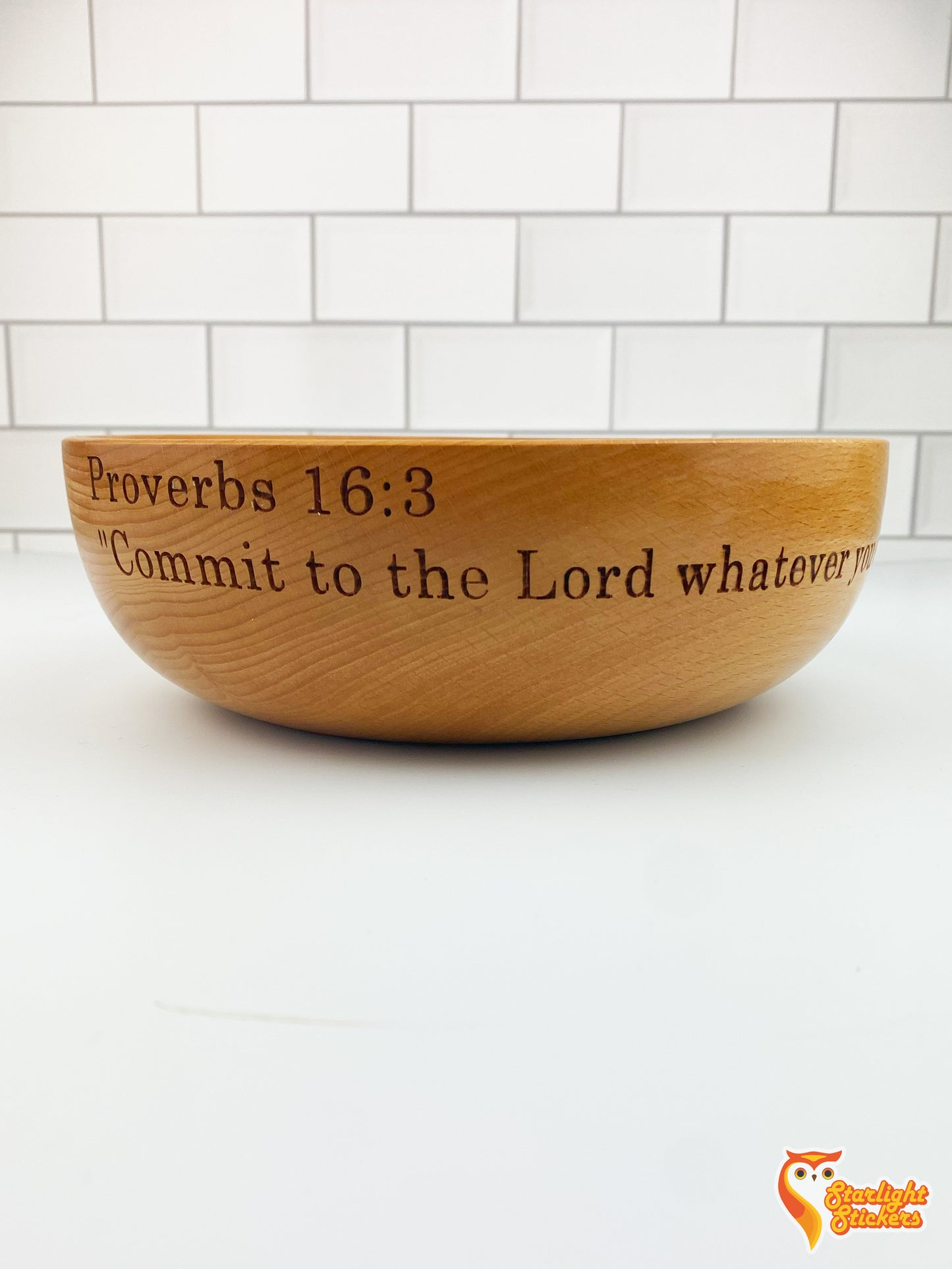 Engraved wooden bowl on a white table with a white tile background.