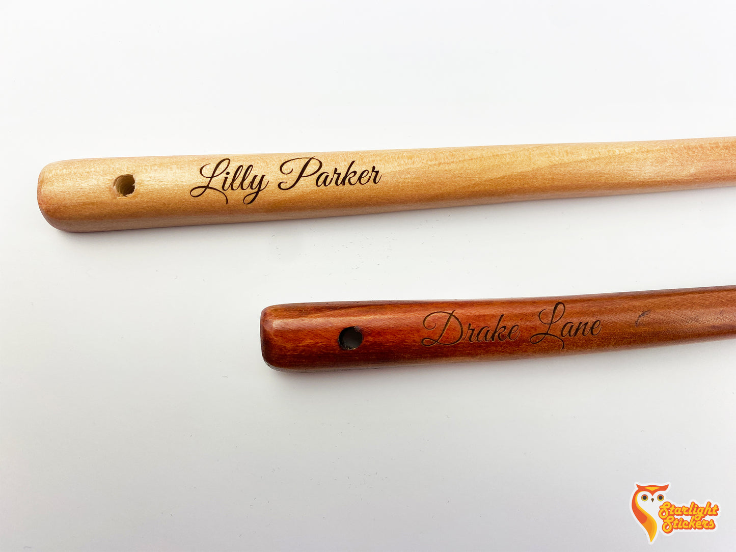 Engraved handles of a light wood and dark wood spoon.
