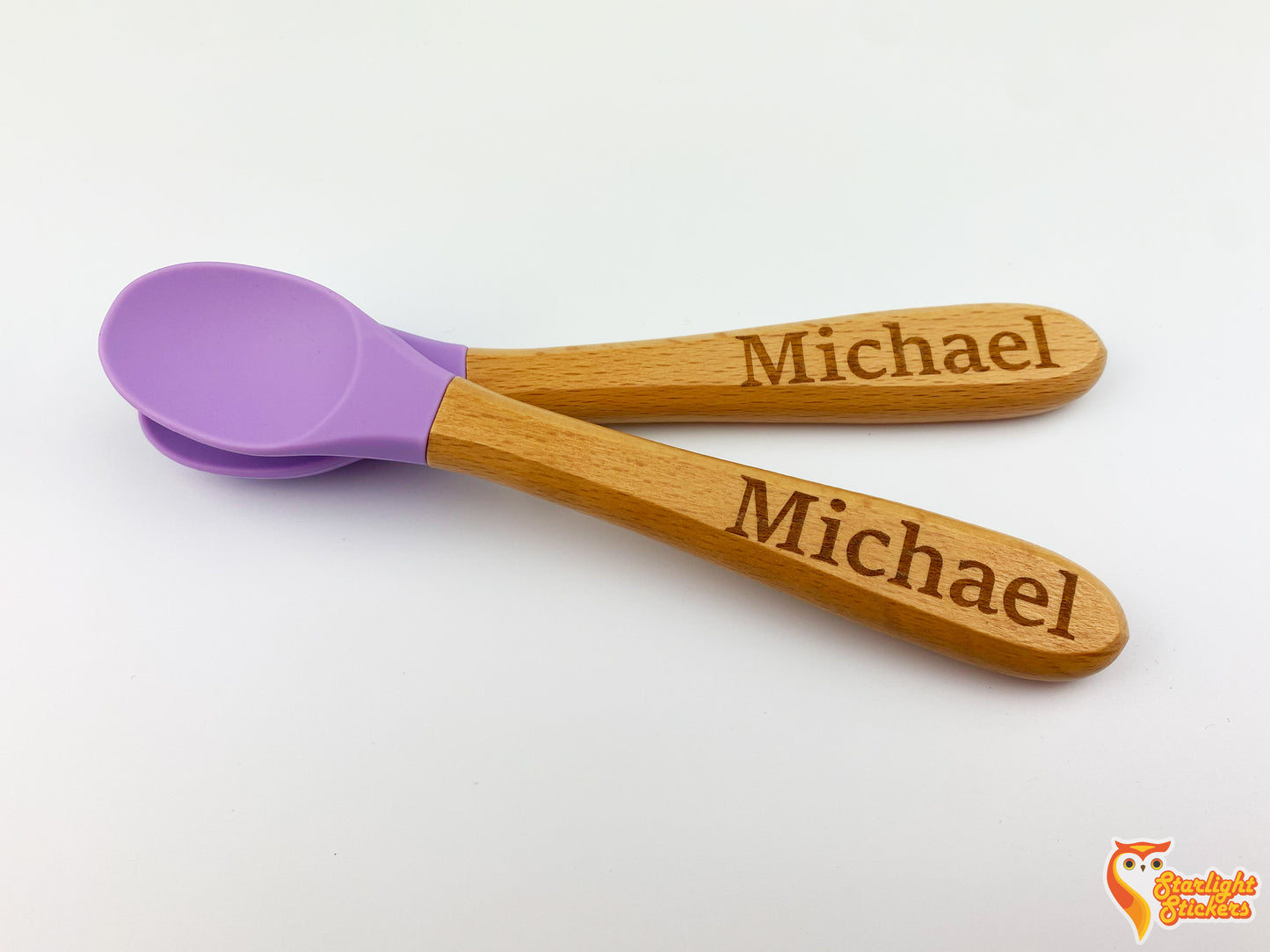 Two baby spoons, one resting on top of the other with a white background.