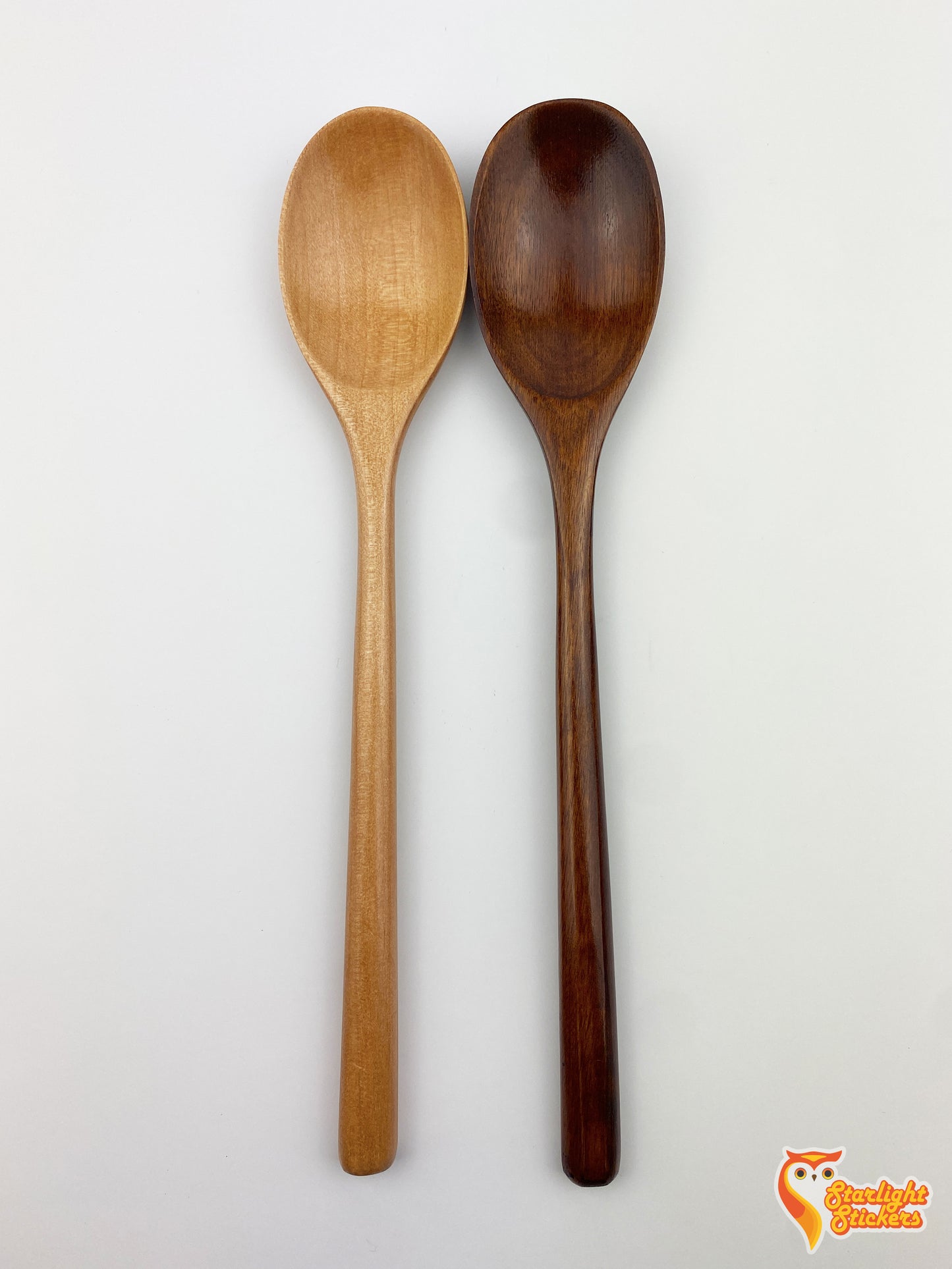 Plain light wood and dark wood spoons next to each other with a white background.