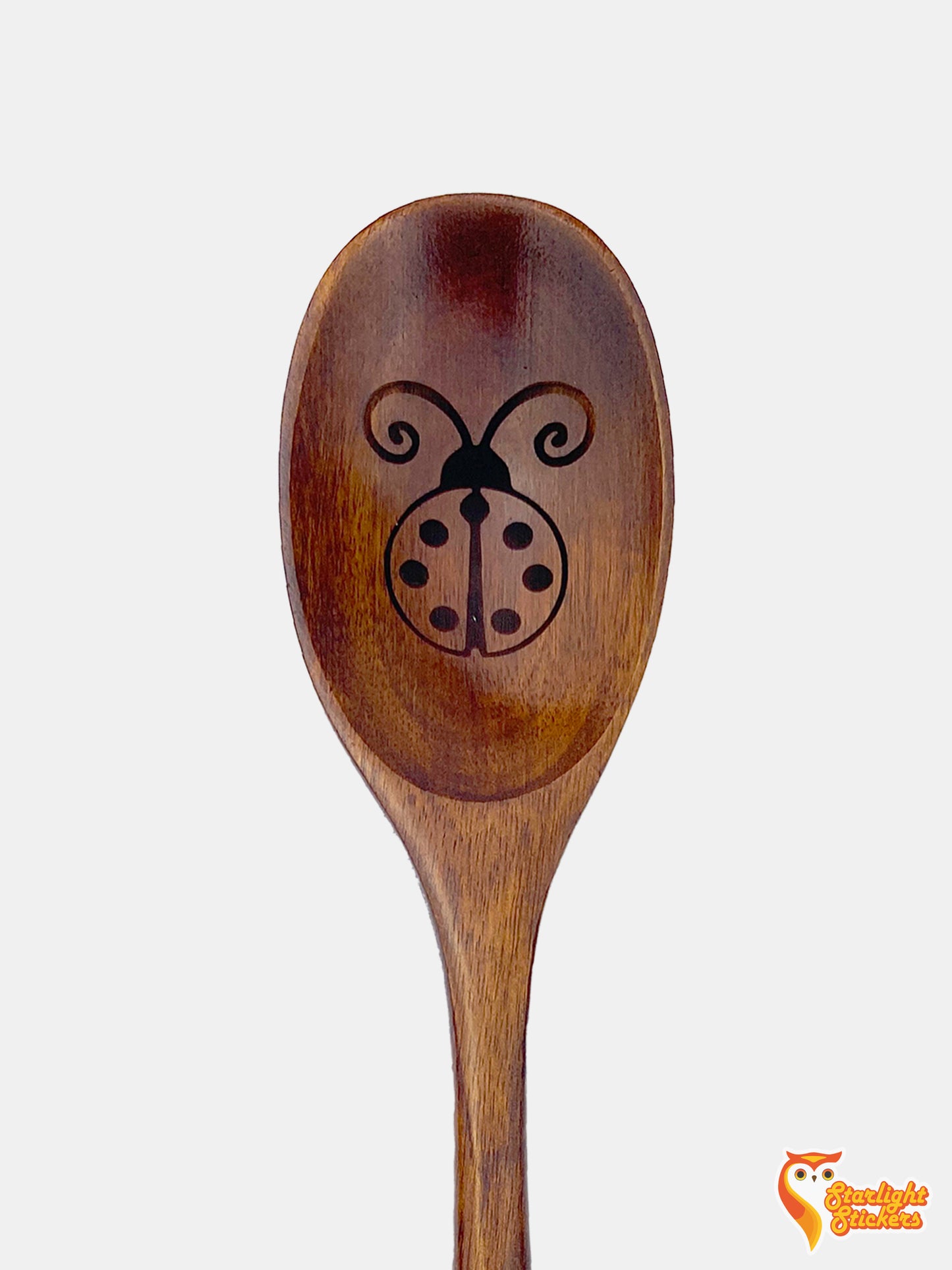 Ladybug engraved in the spoon of a dark wood spoon.