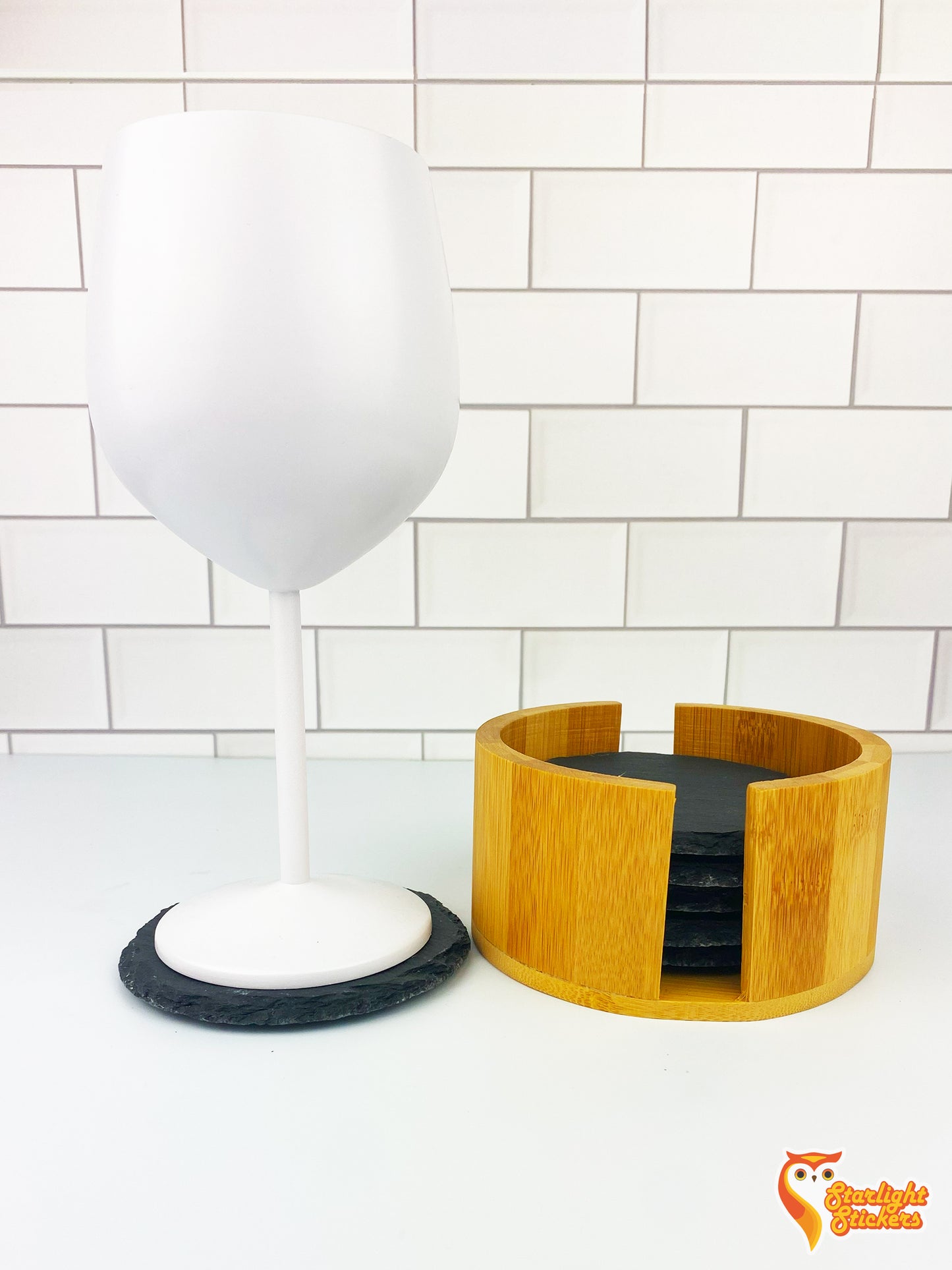 White wine glass on top of circular coaster next to coaster holder.