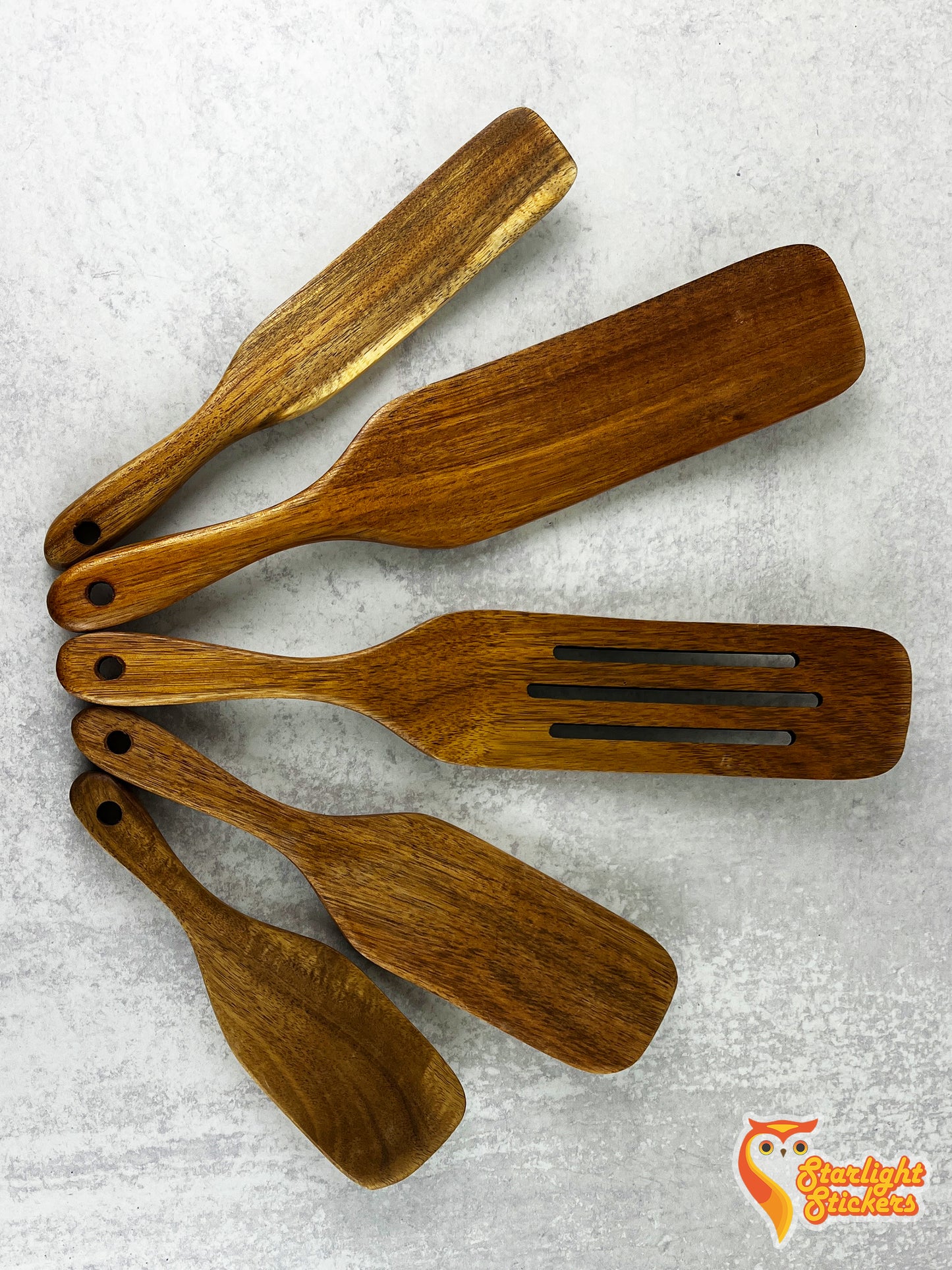 A spurtle set fanned out on a marble background.