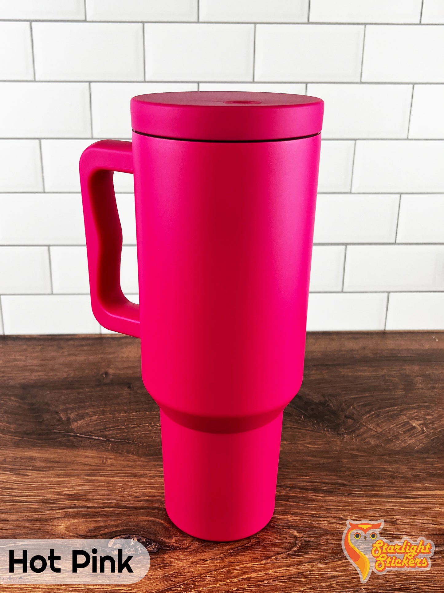 Hot pink tumbler on a wooden table with a white tile background.