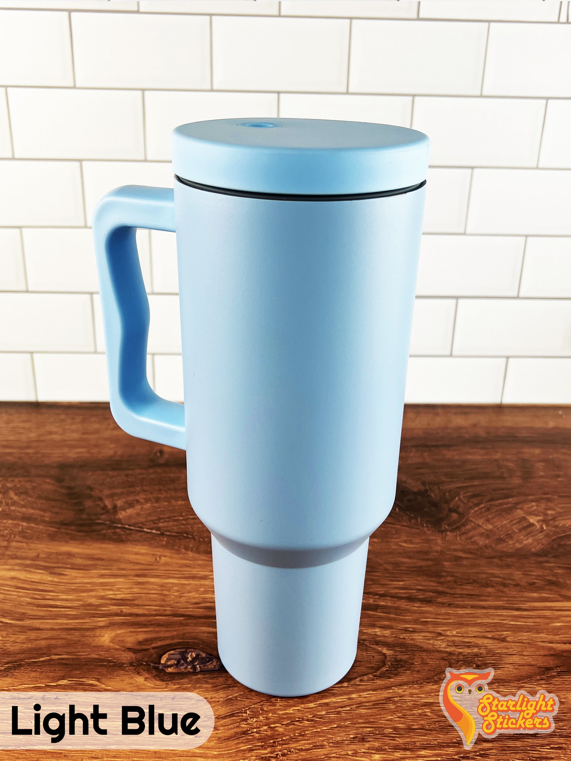 Light blue tumbler on a wooden table with a white tile background.